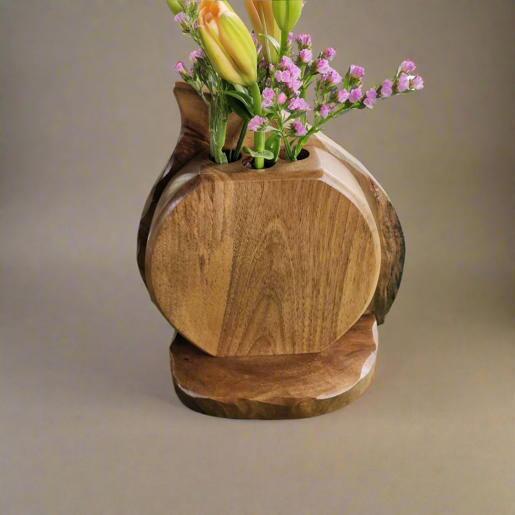 Wooden vase with flowers on a green surface